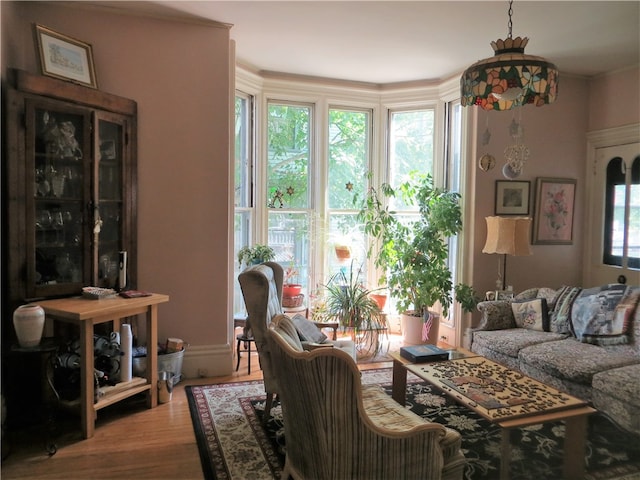 living room with an inviting chandelier, hardwood / wood-style floors, crown molding, and a healthy amount of sunlight