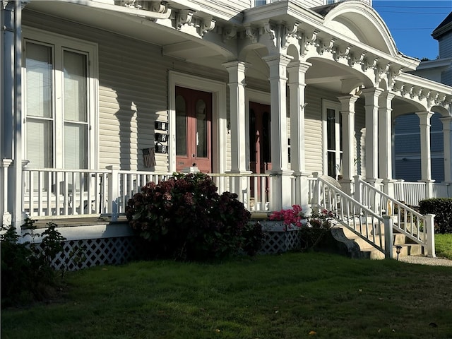 doorway to property with covered porch and a yard