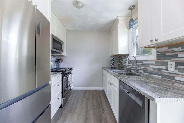 kitchen featuring hardwood / wood-style floors, white cabinets, light stone countertops, sink, and stainless steel appliances