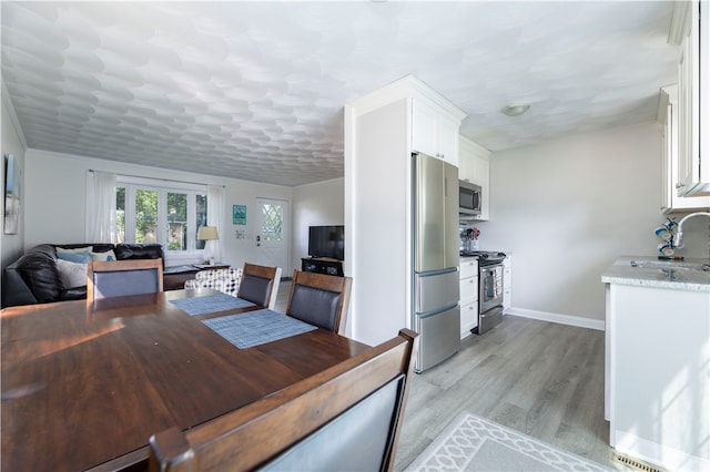 dining room featuring sink and light hardwood / wood-style floors