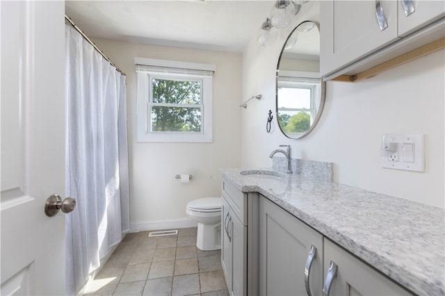 bathroom featuring vanity, toilet, a healthy amount of sunlight, and tile patterned flooring