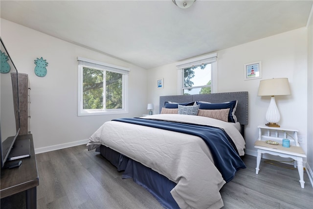 bedroom with hardwood / wood-style flooring, lofted ceiling, and multiple windows