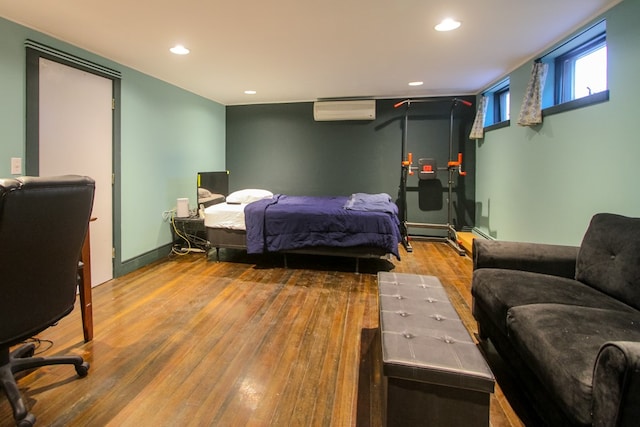 bedroom with hardwood / wood-style flooring and a wall unit AC