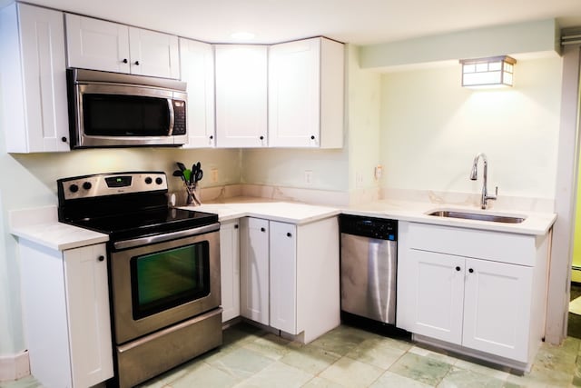 kitchen with white cabinetry, light stone counters, appliances with stainless steel finishes, and sink