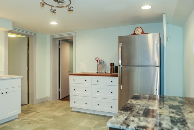 kitchen with stainless steel fridge and white cabinetry