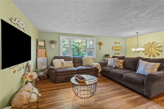 living room with hardwood / wood-style flooring, a textured ceiling, and an inviting chandelier