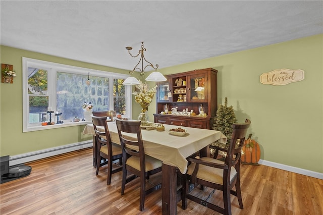 dining space featuring a baseboard heating unit and hardwood / wood-style flooring