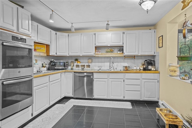 kitchen featuring stainless steel appliances, sink, decorative backsplash, and white cabinets