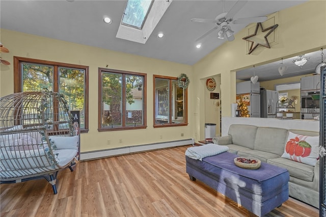 living room featuring high vaulted ceiling, a skylight, a baseboard heating unit, ceiling fan, and light hardwood / wood-style flooring