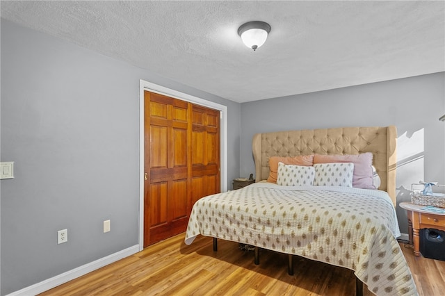 bedroom featuring a closet, hardwood / wood-style floors, and a textured ceiling