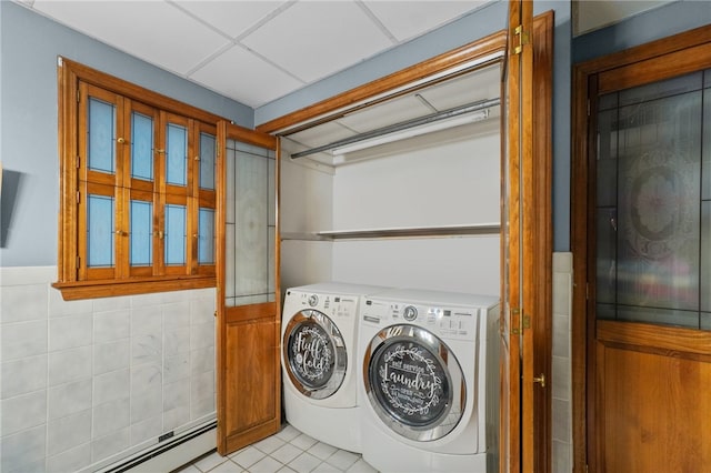 clothes washing area with a baseboard radiator, tile walls, light tile patterned floors, and washing machine and dryer