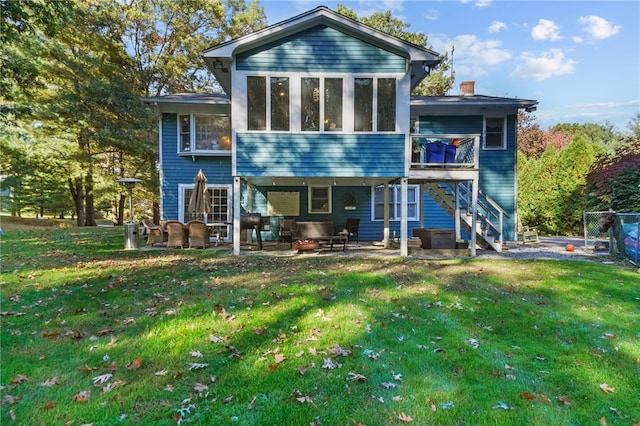 rear view of property featuring a yard, a sunroom, and a patio