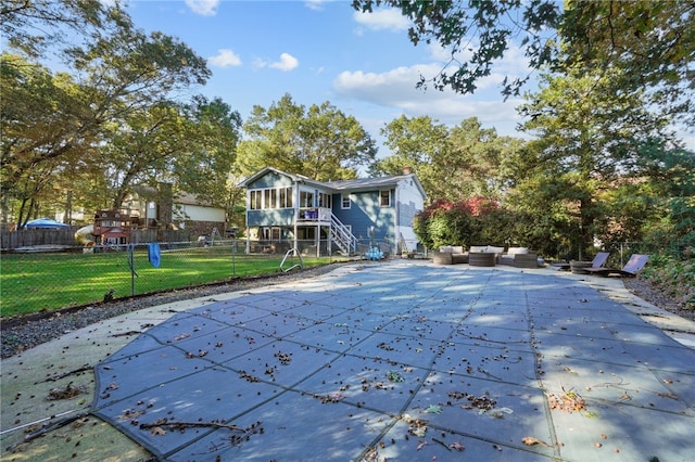 back of house with a lawn, a patio, a sunroom, a covered pool, and an outdoor hangout area