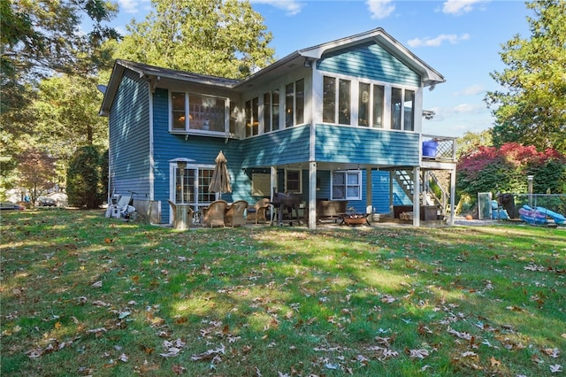 back of house with a patio area, a sunroom, and a lawn