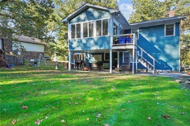 rear view of house with a lawn, a sunroom, and a patio area