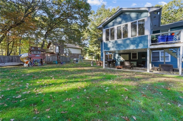 rear view of house featuring a lawn, a playground, and a patio area