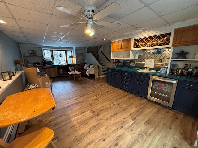 interior space with a paneled ceiling, dishwasher, sink, ceiling fan, and light hardwood / wood-style floors