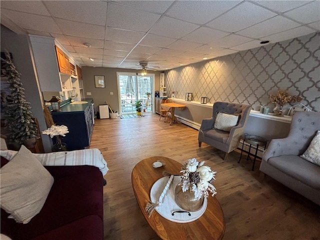 living room featuring a paneled ceiling, sink, a baseboard radiator, and light hardwood / wood-style floors