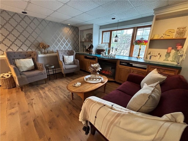 sitting room featuring a drop ceiling, light hardwood / wood-style flooring, and a baseboard radiator