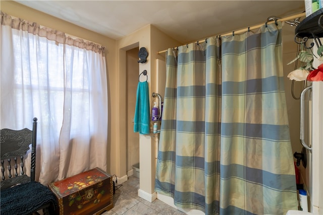 bathroom with curtained shower, toilet, and tile patterned flooring