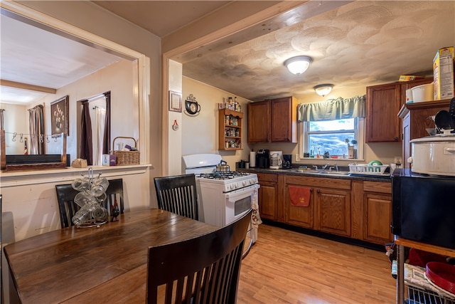 kitchen with sink, light hardwood / wood-style flooring, and gas range gas stove