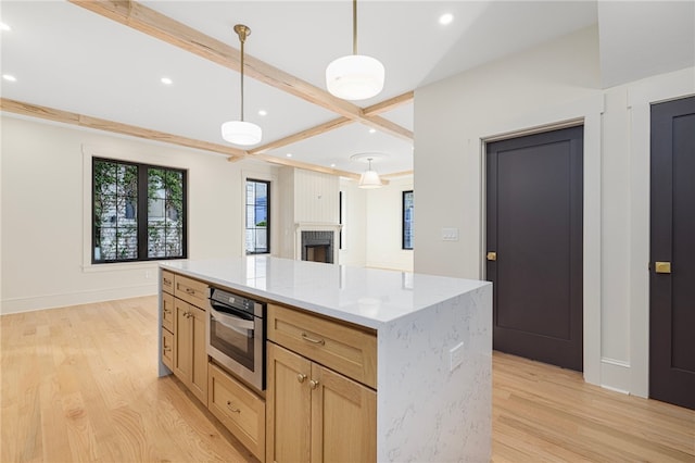 kitchen featuring a kitchen island, stainless steel oven, light brown cabinetry, pendant lighting, and light hardwood / wood-style floors