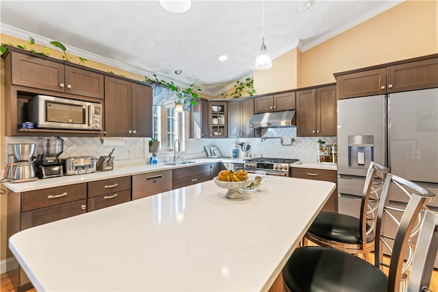 kitchen with sink, backsplash, hanging light fixtures, stainless steel appliances, and ornamental molding