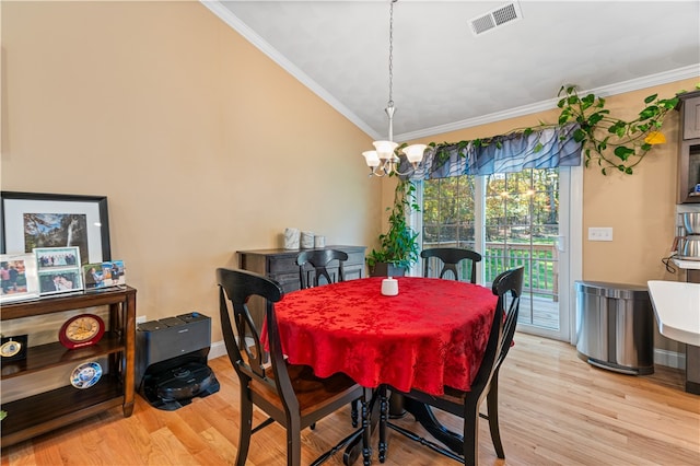 dining area with crown molding, light hardwood / wood-style flooring, and an inviting chandelier