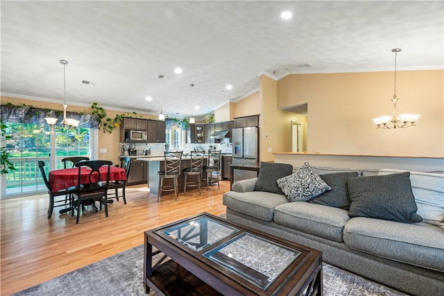 living room with lofted ceiling, a notable chandelier, ornamental molding, and light hardwood / wood-style floors