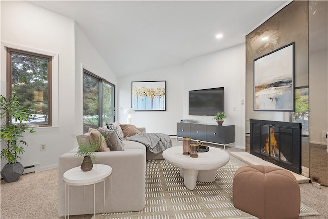 living area featuring carpet flooring, a glass covered fireplace, baseboard heating, and lofted ceiling