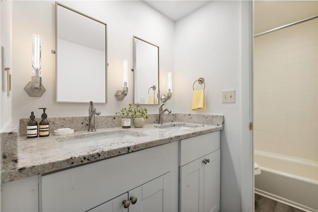 full bathroom featuring double vanity, a sink, shower / bathing tub combination, and wood finished floors
