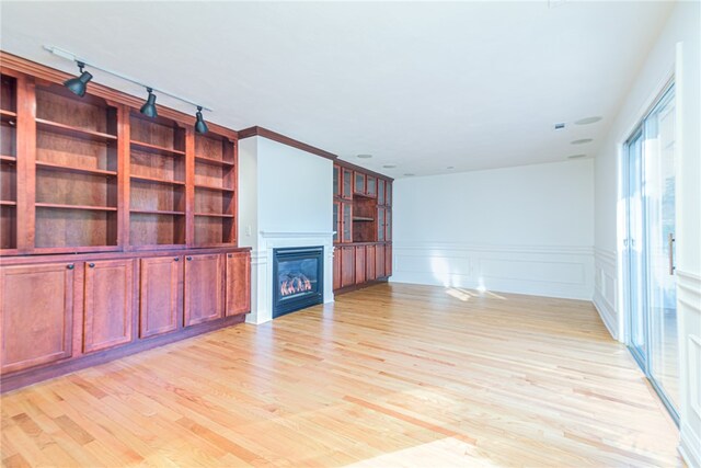 unfurnished living room with ornamental molding and light wood-type flooring