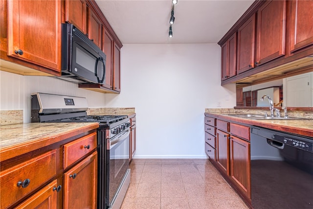 kitchen featuring track lighting, black appliances, sink, and light stone counters