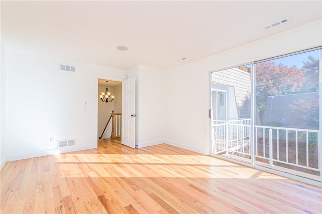 unfurnished room with a notable chandelier, a healthy amount of sunlight, and light wood-type flooring