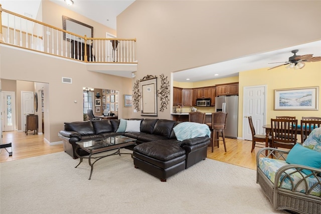 living room featuring a wealth of natural light, light hardwood / wood-style floors, ceiling fan, and high vaulted ceiling