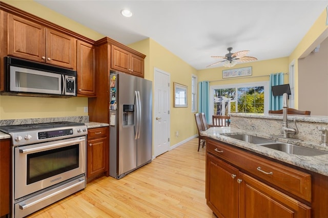 kitchen featuring light hardwood / wood-style floors, stainless steel appliances, light stone counters, sink, and ceiling fan