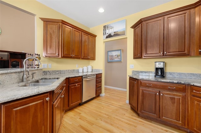 kitchen with stainless steel dishwasher, light hardwood / wood-style floors, sink, and light stone counters