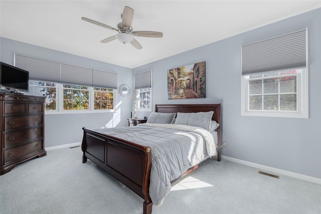 bedroom featuring multiple windows, light colored carpet, and ceiling fan