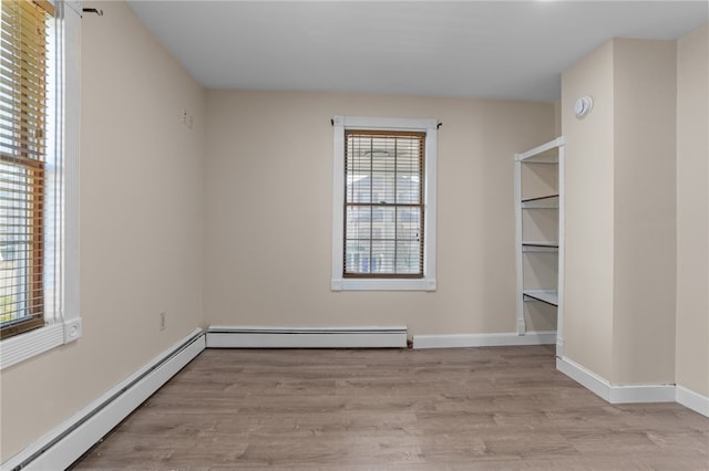 unfurnished room featuring a baseboard radiator and light wood-type flooring