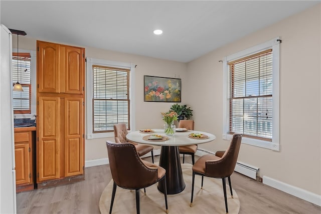 dining space with light wood-type flooring, a baseboard heating unit, and plenty of natural light