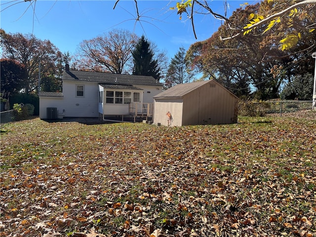 back of house featuring a storage shed, central AC, and a lawn