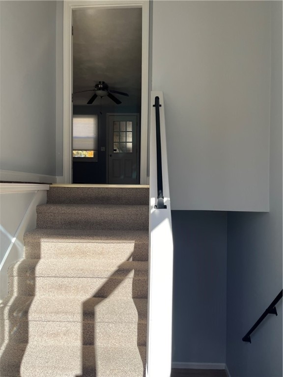 stairway featuring ceiling fan