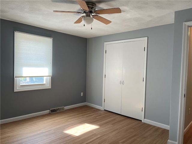 unfurnished bedroom with a closet, ceiling fan, a textured ceiling, and light hardwood / wood-style flooring