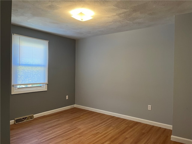 empty room featuring a textured ceiling and hardwood / wood-style flooring