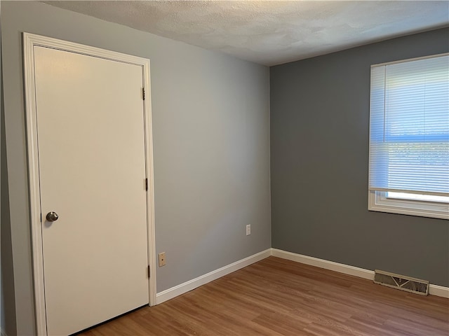 spare room with a textured ceiling and light hardwood / wood-style floors