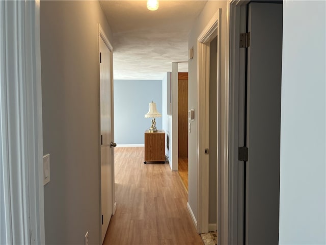 corridor featuring a textured ceiling and light hardwood / wood-style floors