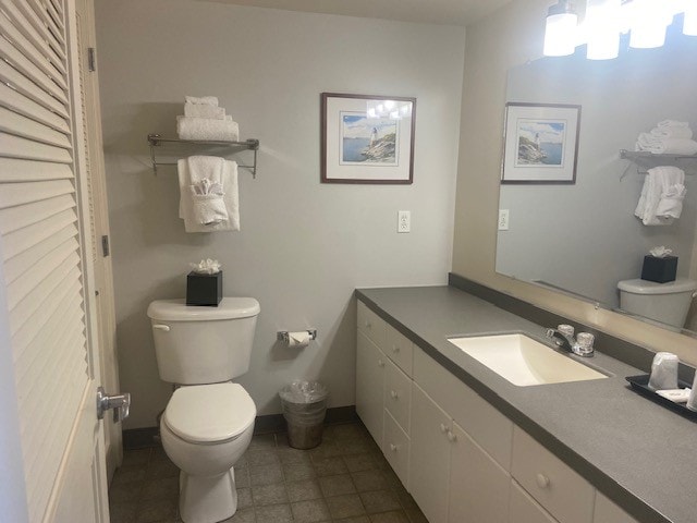 bathroom with toilet, vanity, and tile patterned flooring