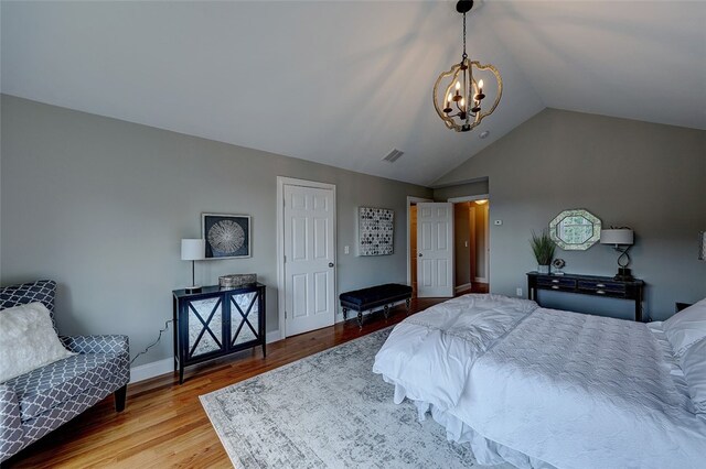 bedroom with light hardwood / wood-style floors, lofted ceiling, and a chandelier