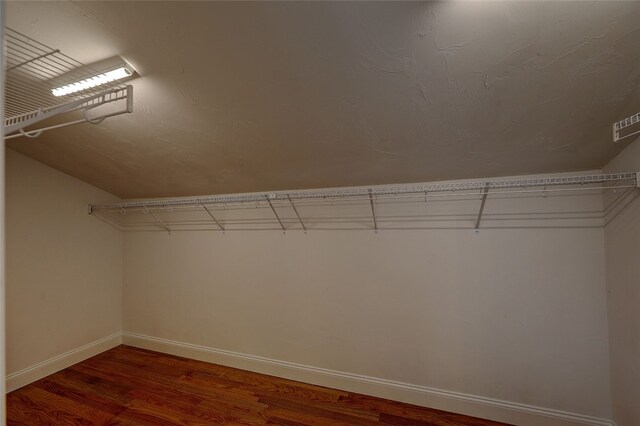 spacious closet with hardwood / wood-style floors and vaulted ceiling