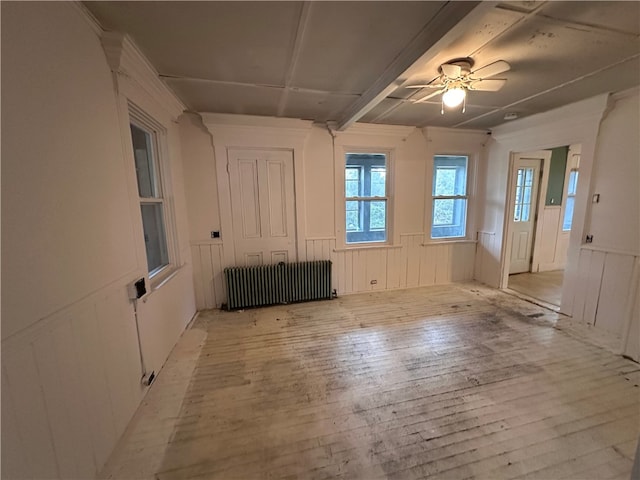 spare room featuring radiator heating unit, light wood-type flooring, and ceiling fan